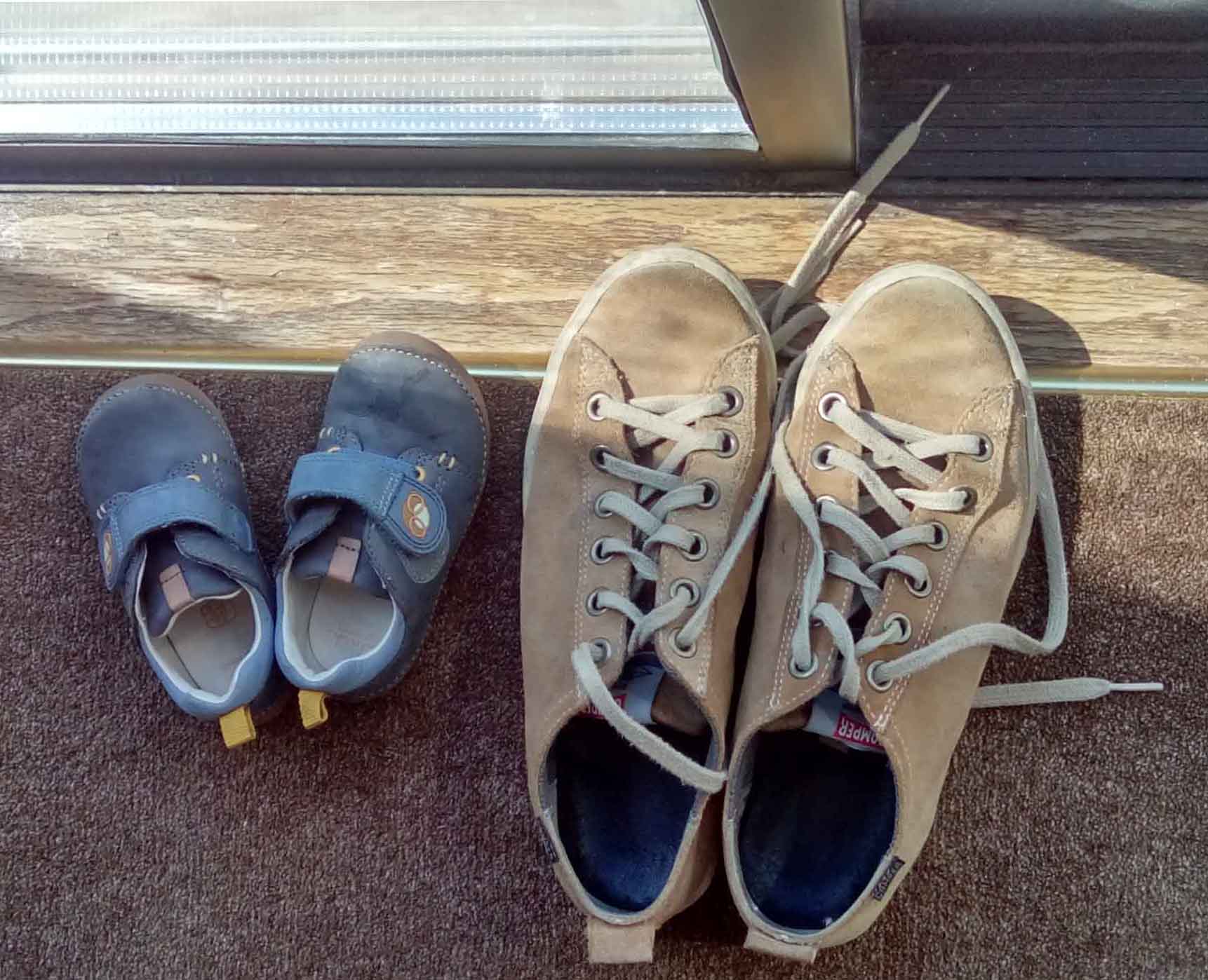 Baby shoes beside adult shoes